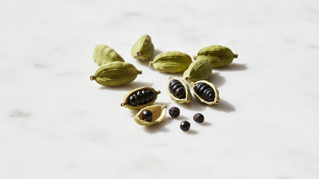 Green cardamom pods split open on marble surface