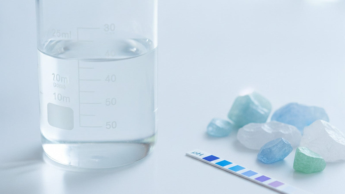Laboratory beaker with clear liquid next to mineral crystals and pH test strip