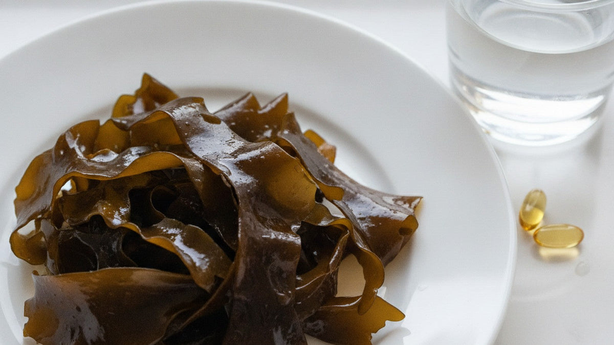 Brown seaweed on white plate with supplement capsules