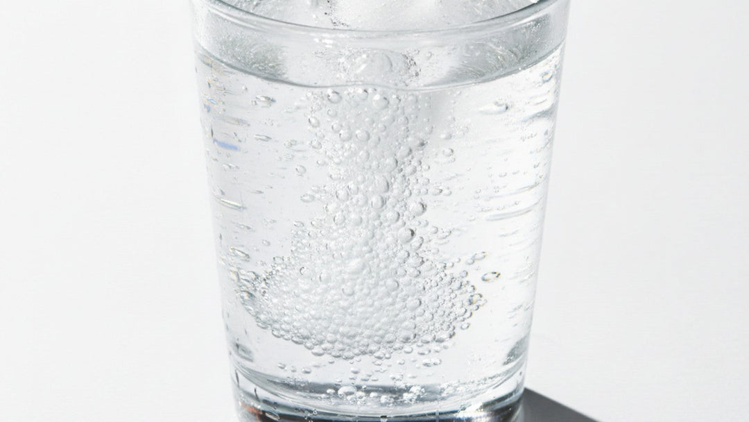 Glass of water with dissolving electrolyte tablet and ice
