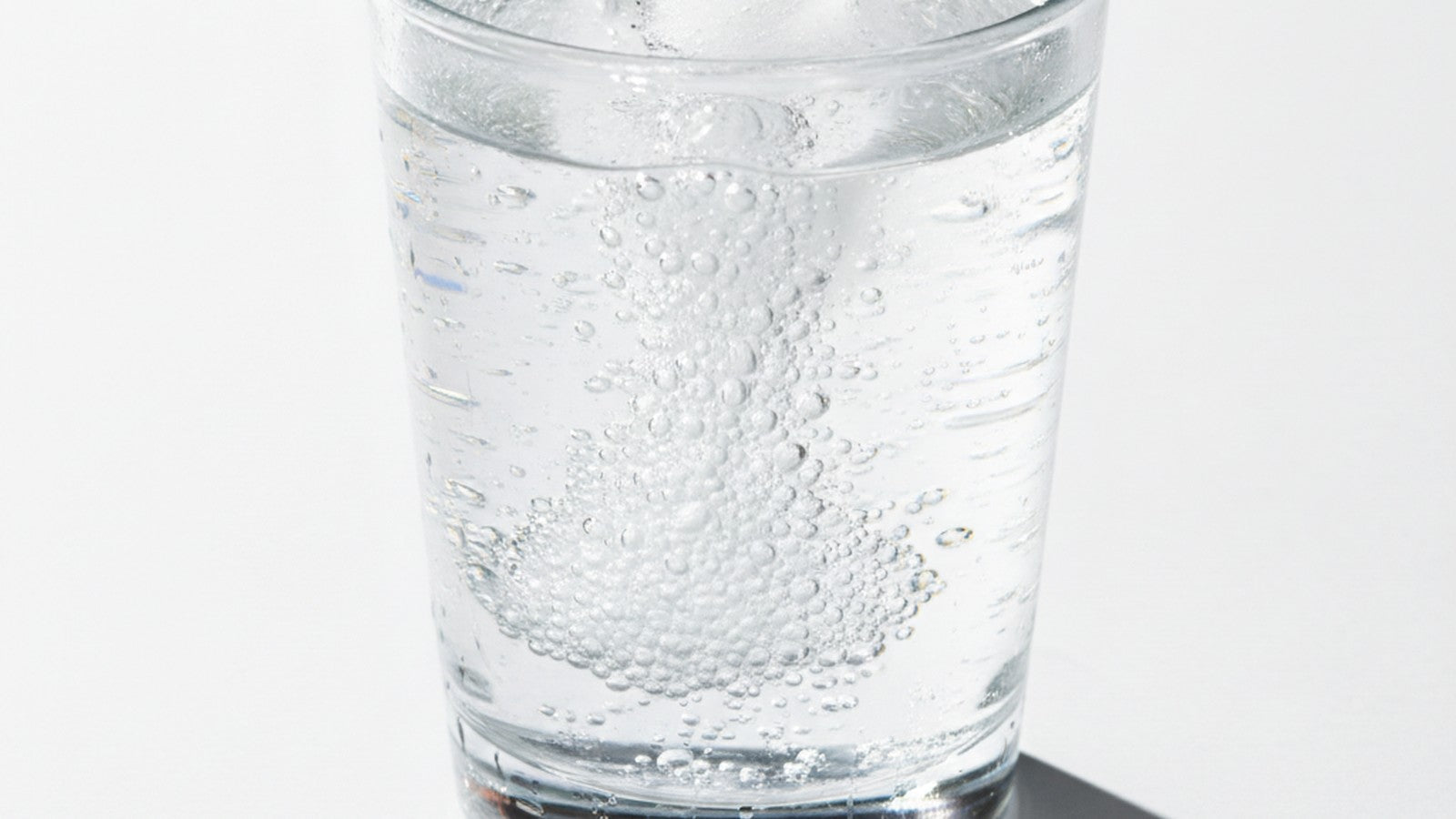 Glass of water with dissolving electrolyte tablet and ice