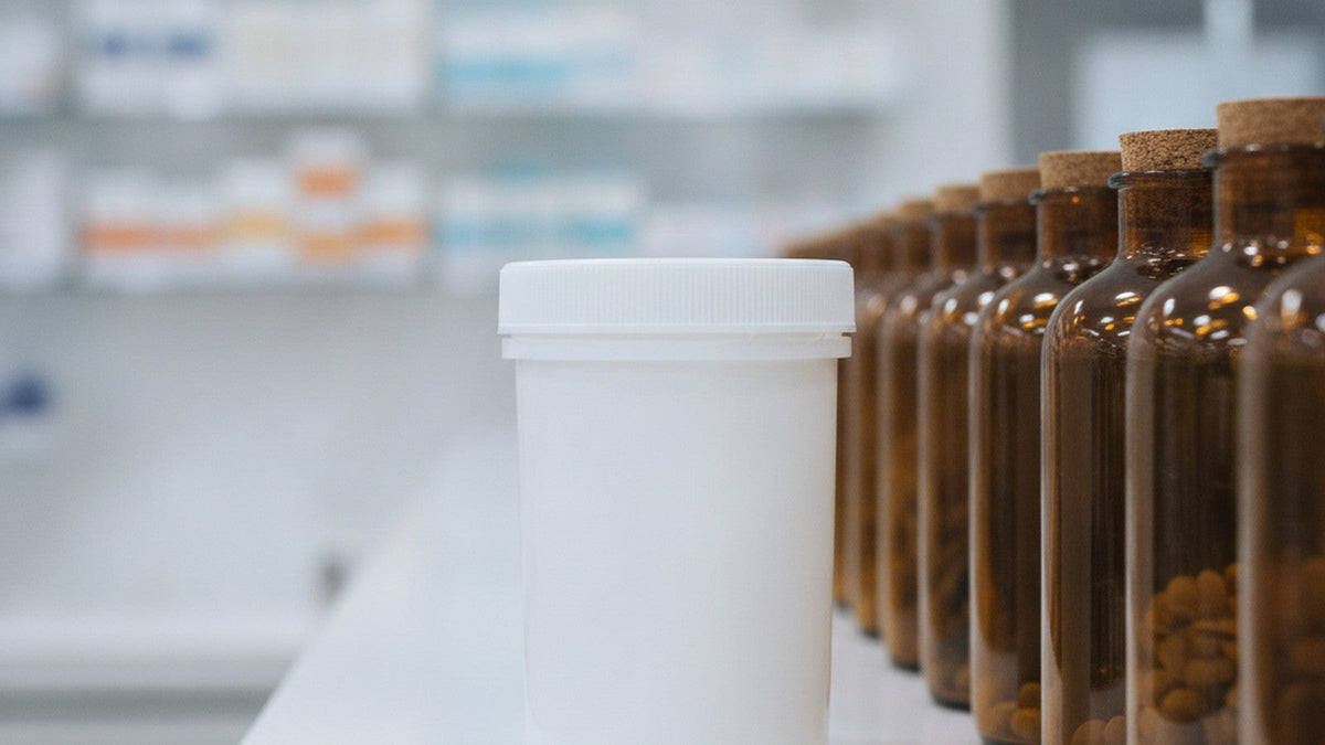 Medical specimen container beside supplement bottles on counter