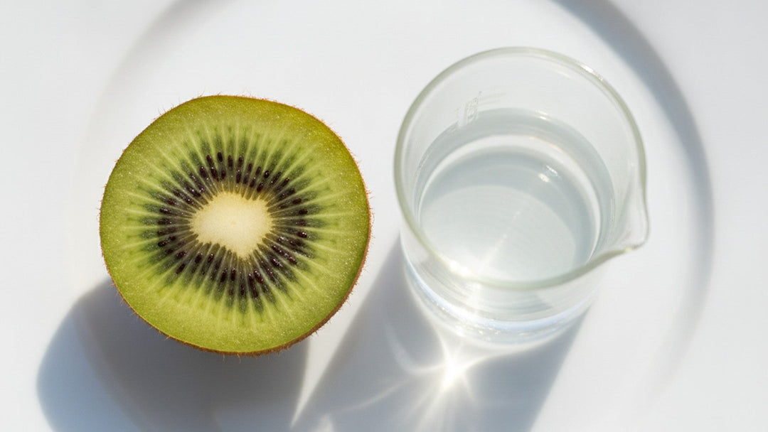 Sliced green kiwifruit beside laboratory beaker on white plate