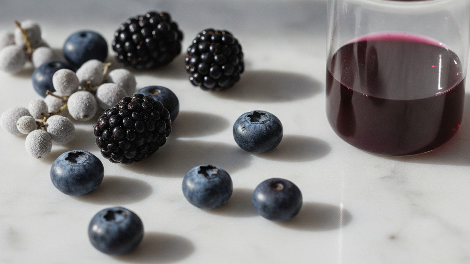 Fresh berries and purple flavonoid extract on marble surface
