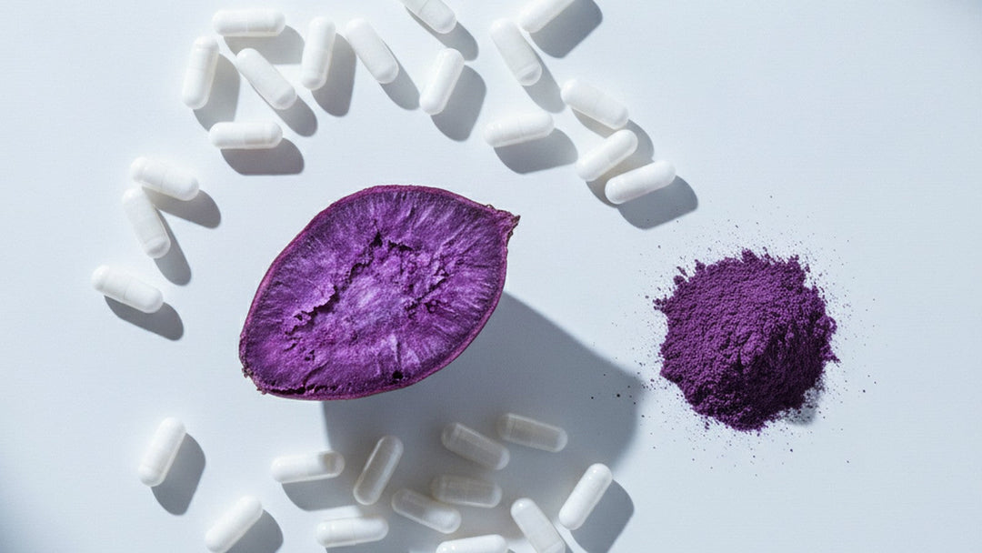 Purple sweet potato cut in half next to white capsules and purple powder on white surface