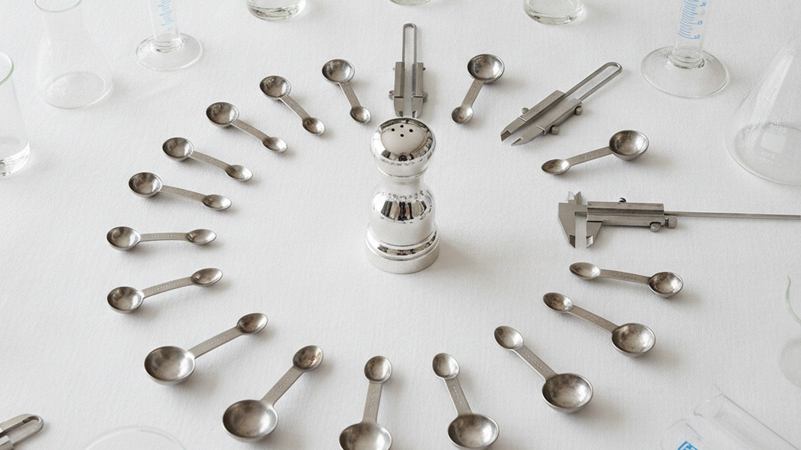 Salt shaker surrounded by measuring instruments on white tablecloth