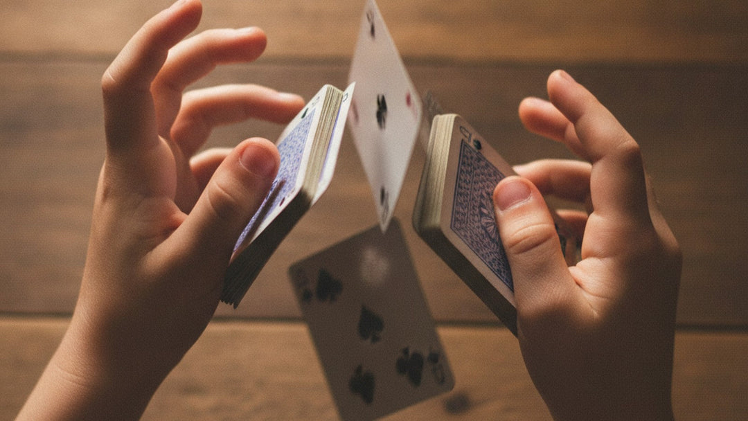 Child's hands shuffling a deck of playing cards on a wooden table