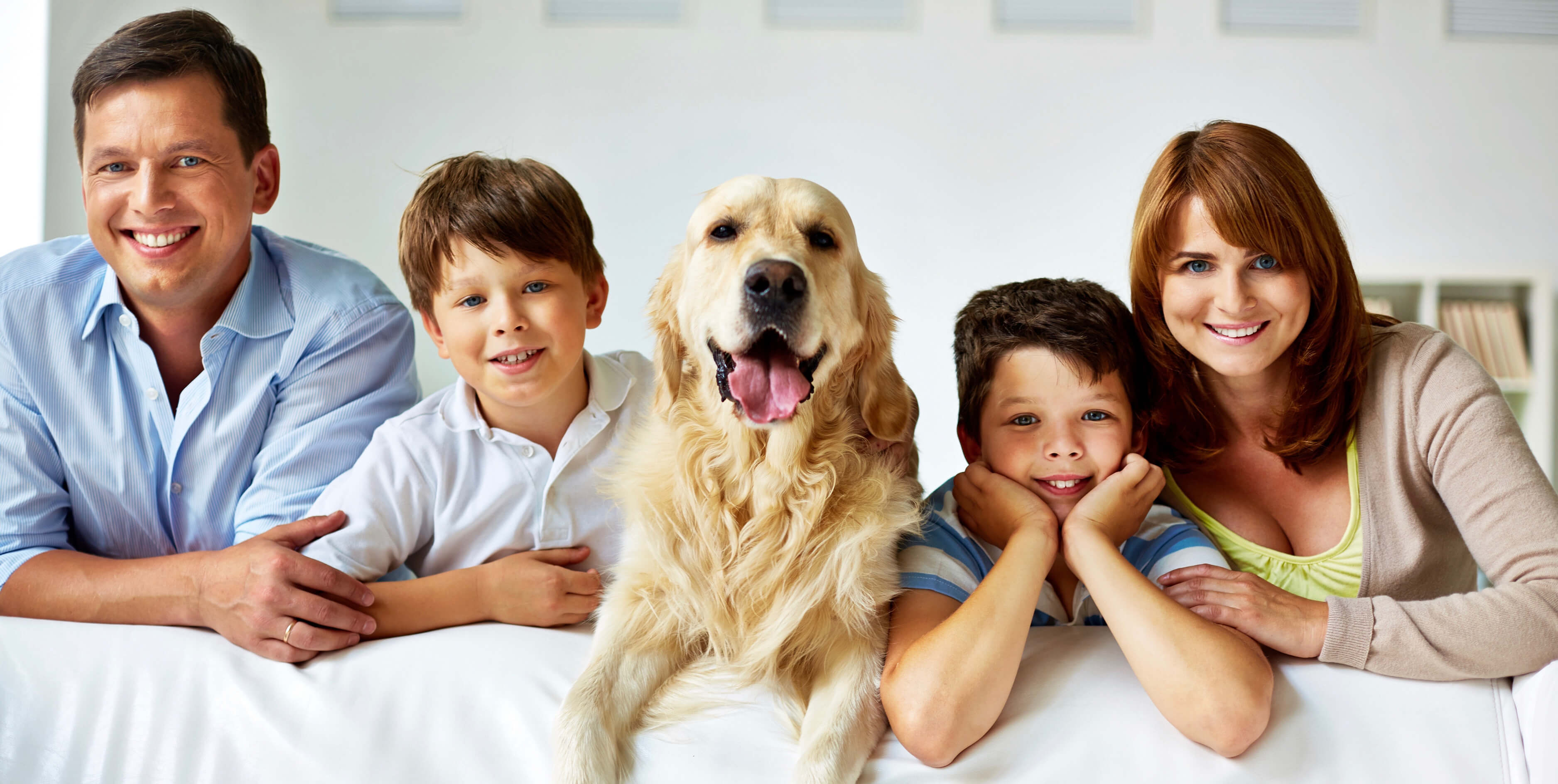 Family of four with a dog sitting on a bed
